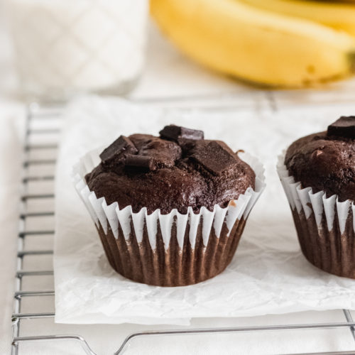banana chocolate muffin next to a glass of milk and a banana