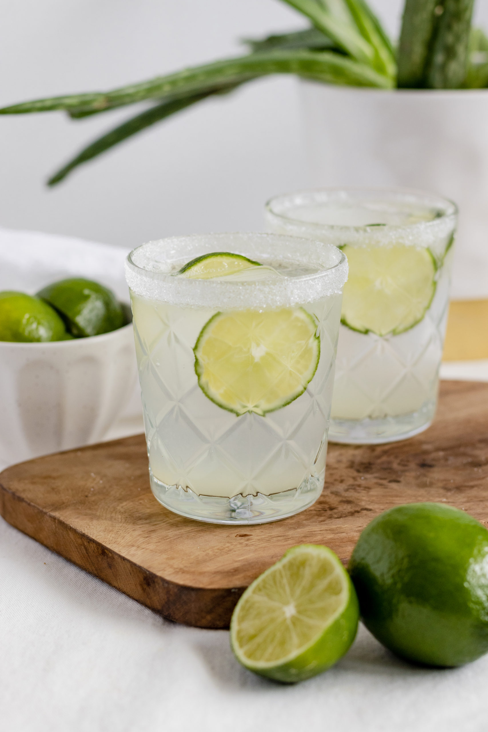 two tequila cocktails with lime slices 